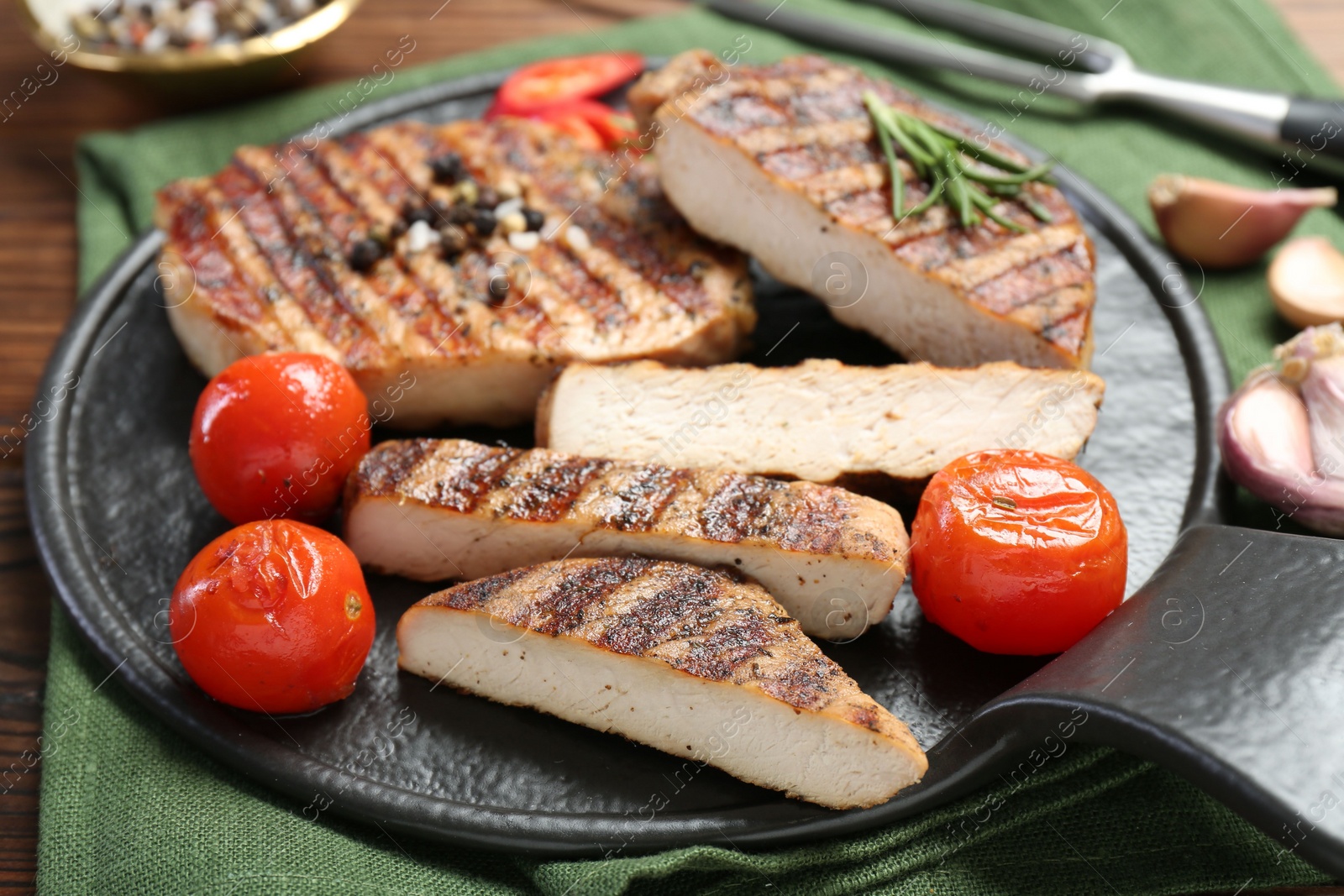Photo of Grilled pork steaks with rosemary, spices and tomatoes on table, closeup