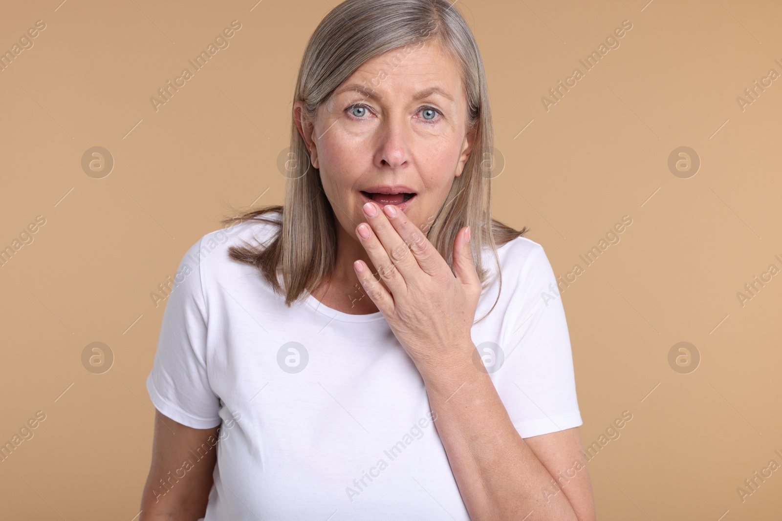 Photo of Portrait of surprised senior woman on beige background