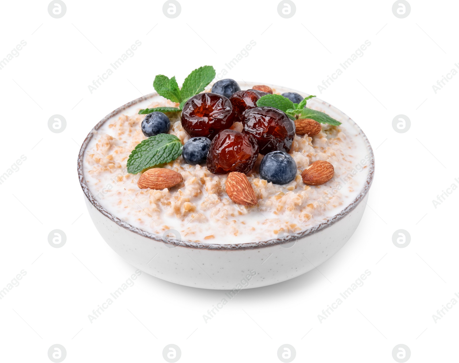 Photo of Tasty wheat porridge with milk, dates, blueberries and almonds in bowl isolated on white