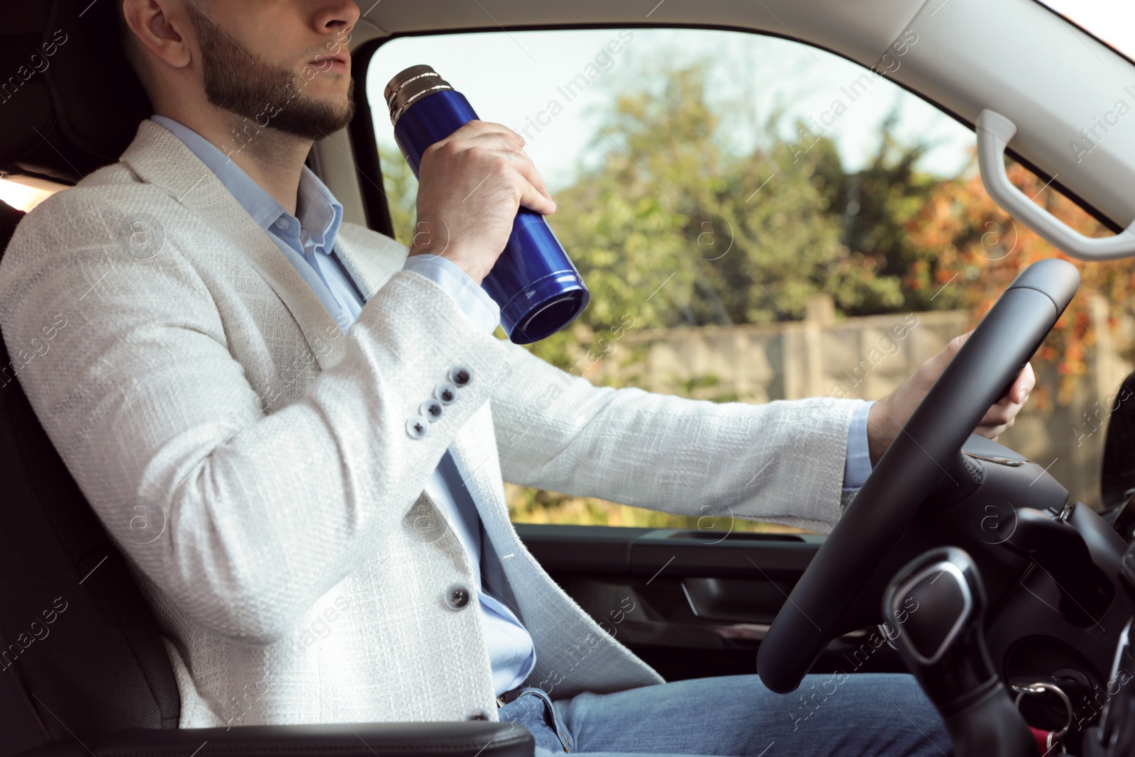 Photo of Man with thermos driving car, closeup view