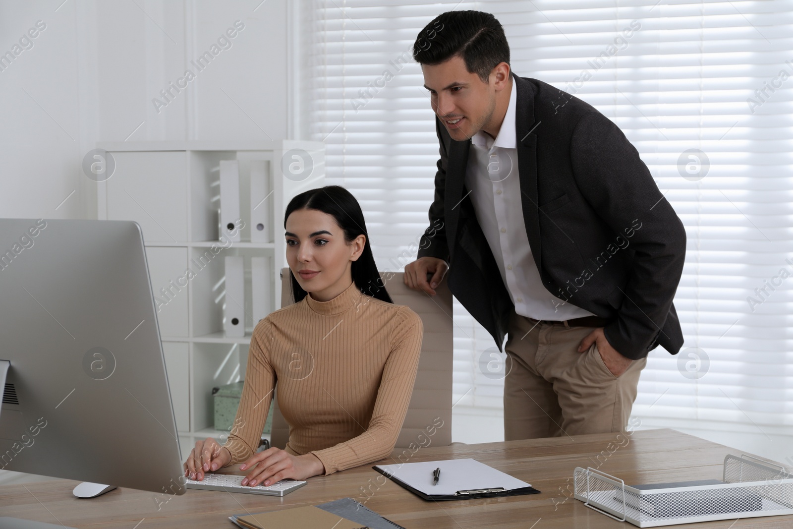 Photo of Secretary and her boss working at table in office