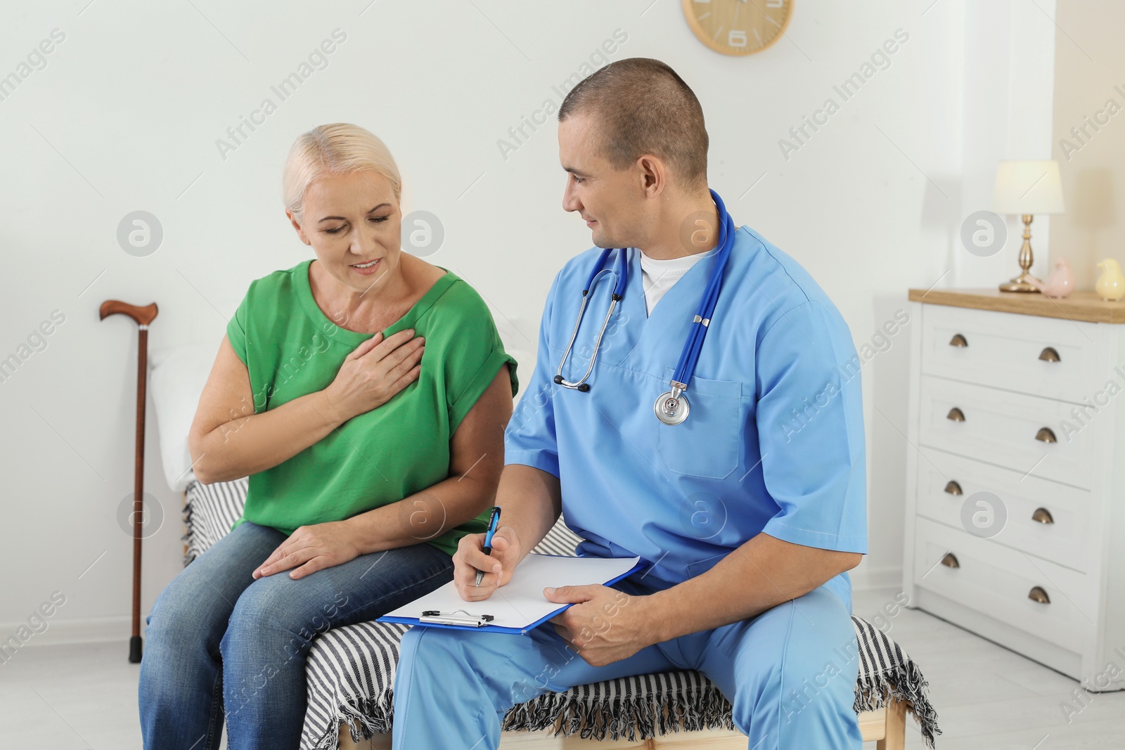 Photo of Male medical assistant consulting female patient during home visit