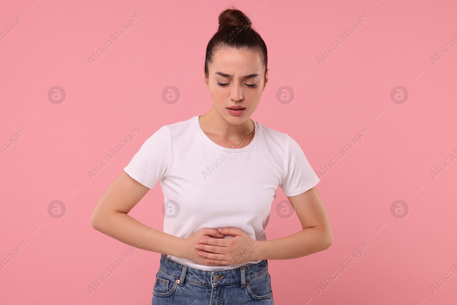 Photo of Woman suffering from abdominal pain on pink background. Unhealthy stomach