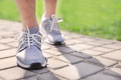 Photo of Sporty young man in training shoes outdoors, closeup