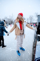 Image of Young woman near fence at ice skating rink