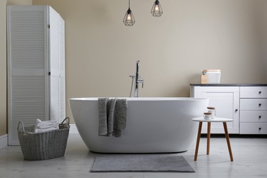 Soft grey mat on floor near tub in bathroom. Interior design