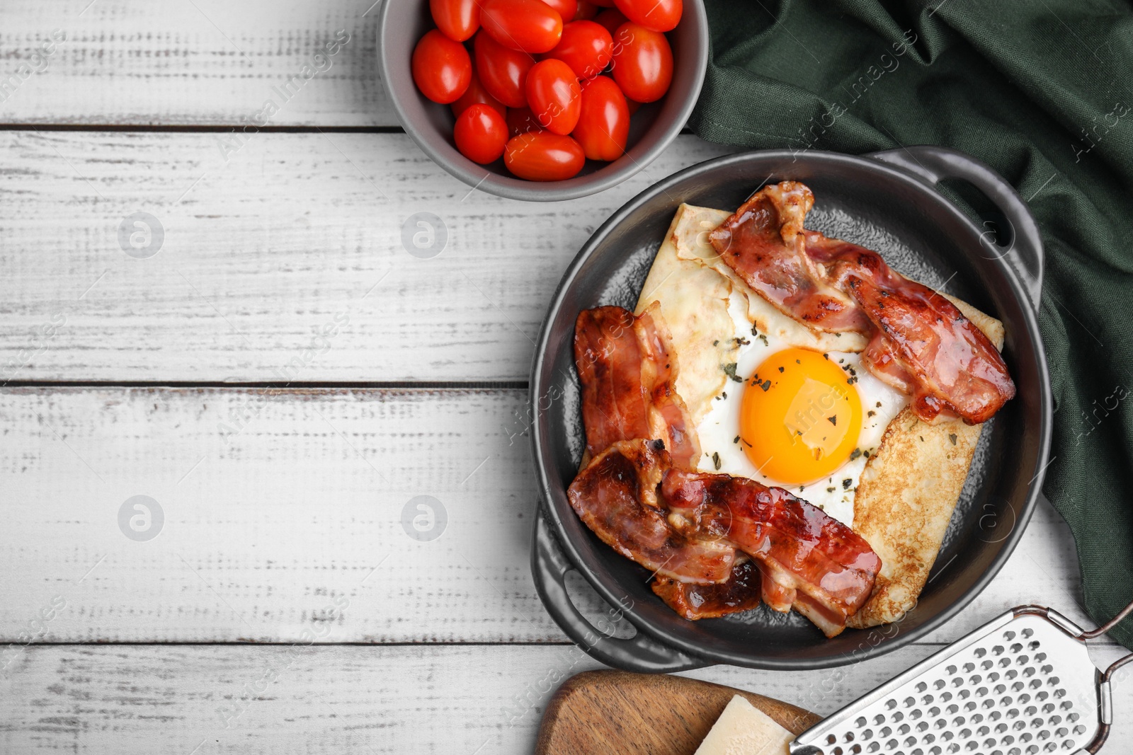 Photo of Delicious crepe with egg and bacon in dish on white wooden table, flat lay with space for text. Breton galette