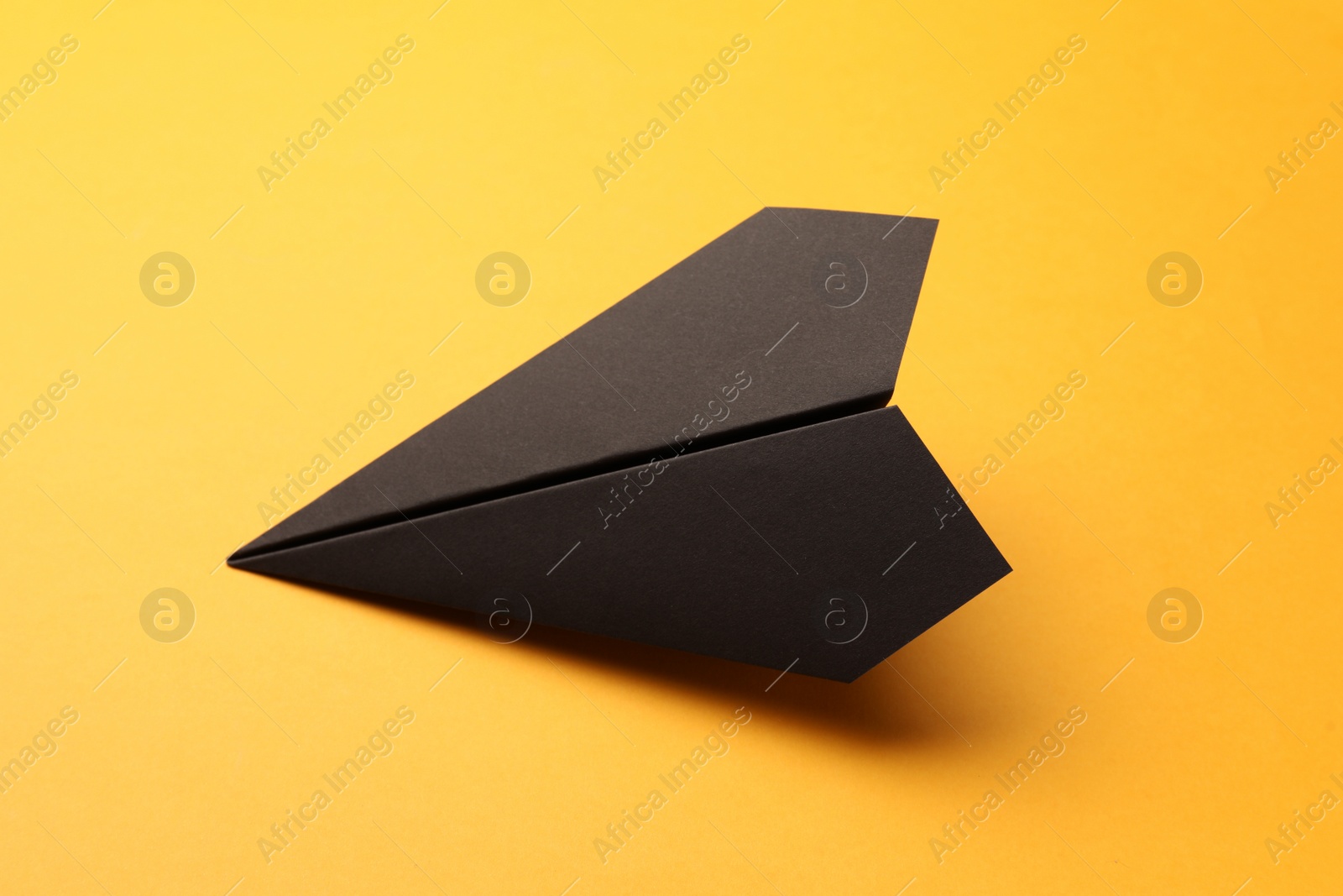 Photo of Handmade black paper plane on yellow background