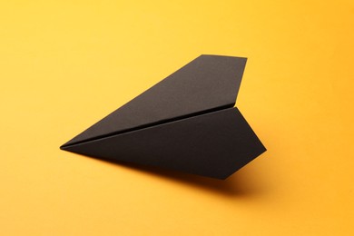 Handmade black paper plane on yellow background