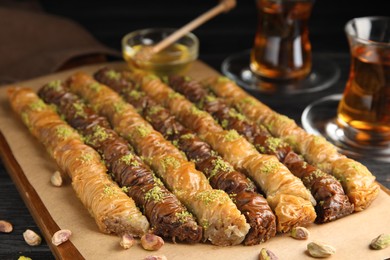 Photo of Delicious sweet baklava with pistachios on wooden board, closeup