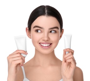 Photo of Teenage girl holding tubes of foundation on white background