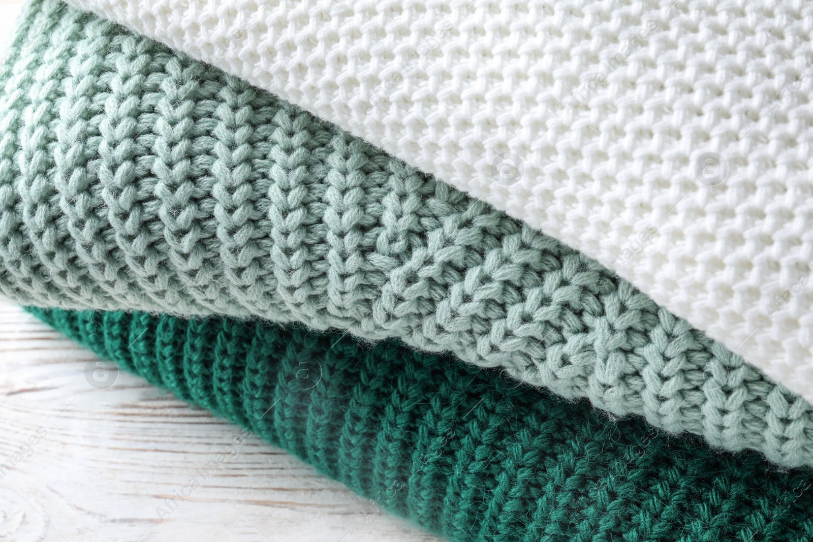 Photo of Stack of soft knitted sweaters on table, closeup