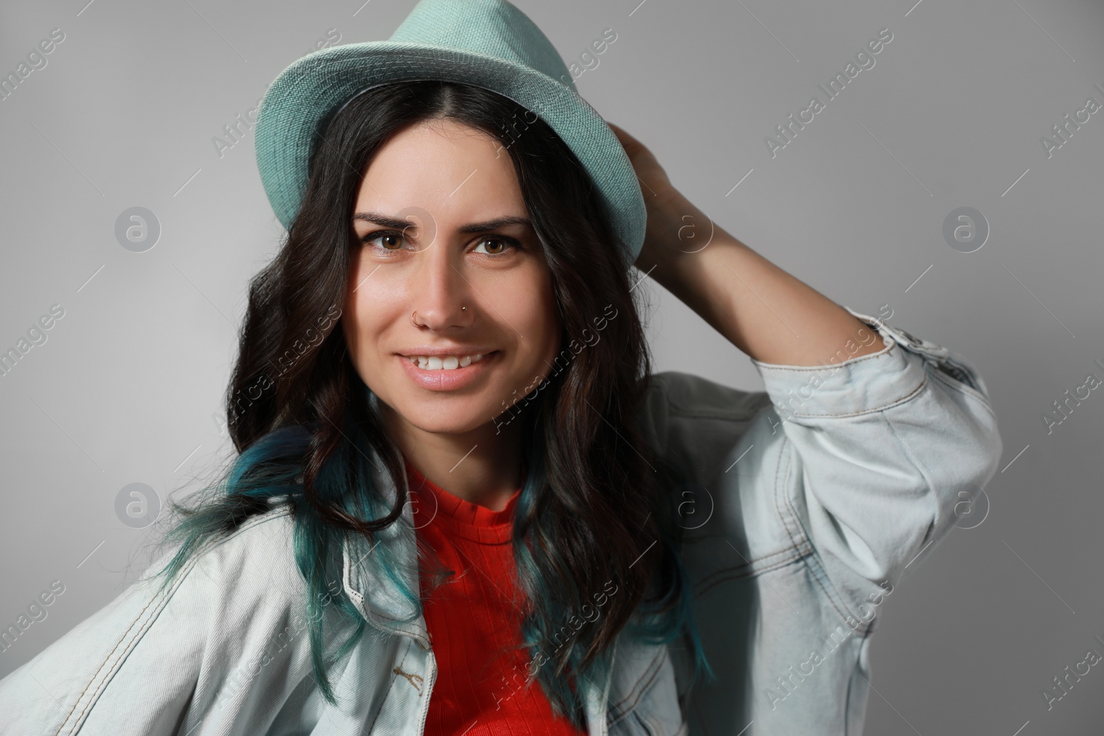 Photo of Beautiful young woman with nose piercing on grey background