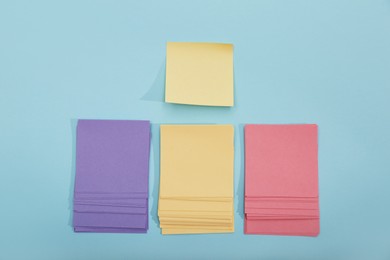 Colorful sticky notes on light blue background, flat lay