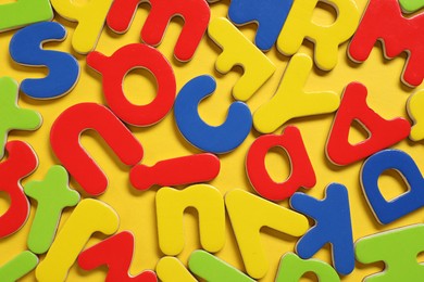 Learning alphabet. Magnetic letters on yellow background, flat lay