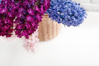 Photo of beautiful hyacinths in wicker pot on table, space for text. Spring flowers