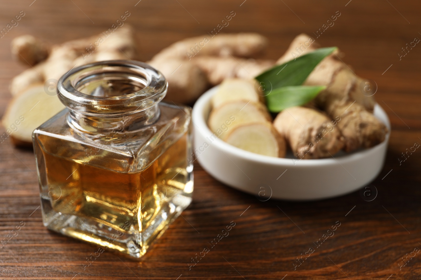 Photo of Ginger essential oil in bottle on wooden table. Space for text