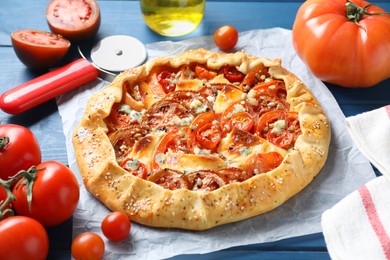 Photo of Tasty galette with tomato and cheese (Caprese galette) on blue wooden table, closeup