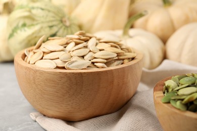Photo of Wooden bowls with pumpkin seeds on table, closeup
