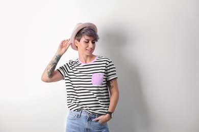 Photo of Trendy young woman with tattoos on white background