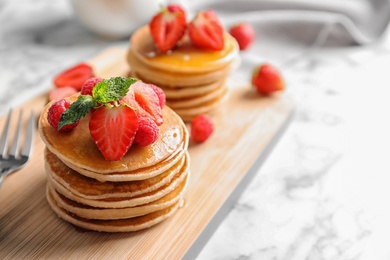 Photo of Tasty pancakes with berries on wooden board