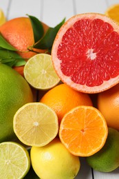 Photo of Different citrus fruits with fresh leaves, closeup