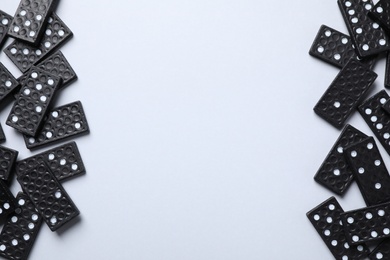 Photo of Black domino tiles on white background, flat lay. Space for text