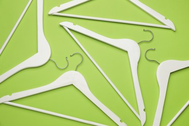 Photo of Empty clothes hangers on green background, flat lay