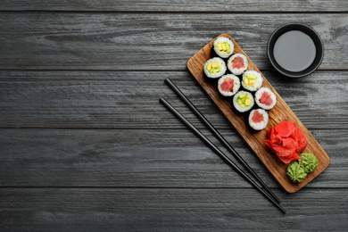 Photo of Delicious sushi rolls on grey wooden table, flat lay. Space for text