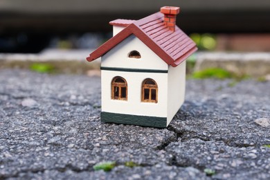 Photo of House model on cracked asphalt. Earthquake disaster
