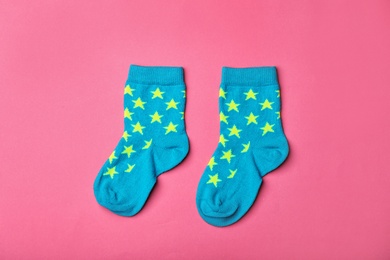 Pair of cute child socks on color background, top view