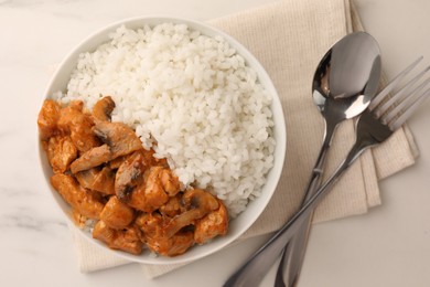 Bowl of delicious rice with meat and mushrooms served on white marble table, flat lay