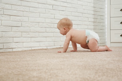 Cute little baby crawling on carpet near brick wall, space for text