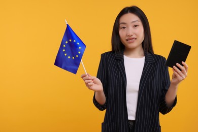 Photo of Immigration to European Union. Happy woman with passport and flag on orange background, space for text
