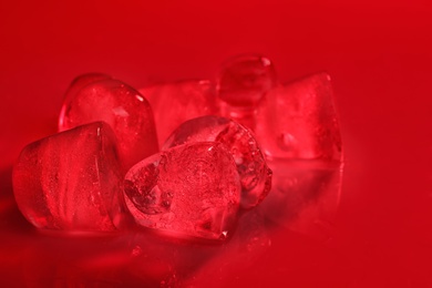 Photo of Melting ice cubes on color background. Frozen liquid