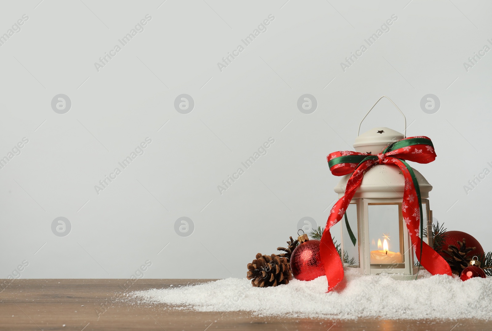 Photo of Decorative lantern and Christmas decor on wooden table against light grey background. Space for text