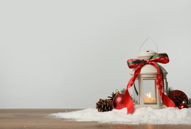Photo of Decorative lantern and Christmas decor on wooden table against light grey background. Space for text