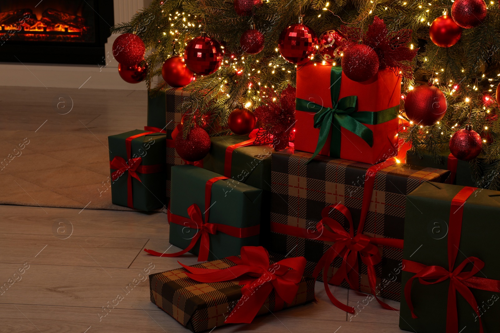 Photo of Many gift boxes under decorated Christmas tree indoors