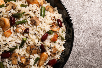 Photo of Delicious rice pilaf with chicken and vegetables on grey table, closeup