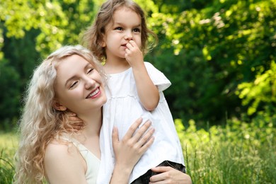 Happy mother with her cute daughter spending time together outdoors, space for text