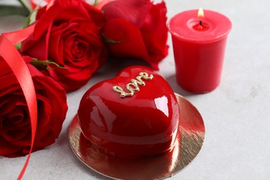 Photo of St. Valentine's Day. Delicious heart shaped cake, roses and candle on light table, closeup