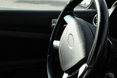 Photo of Black steering wheel in car, closeup. Space for text