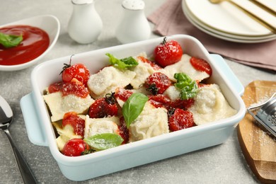 Tasty ravioli with tomato sauce served on grey table