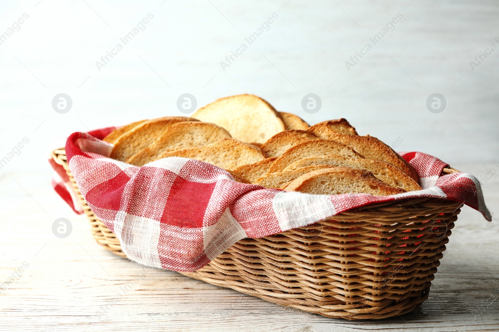 Photo of Slices of toasted bread in basket on white wooden table