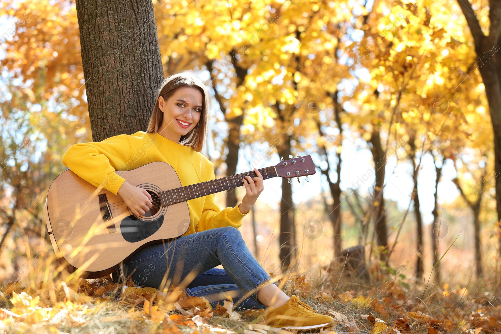 Photo of Teen girl playing guitar in autumn park