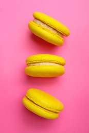 Delicious yellow macarons on pink background, flat lay