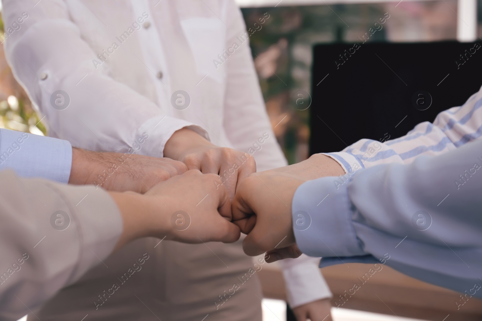 Photo of People holding fists together in office, closeup