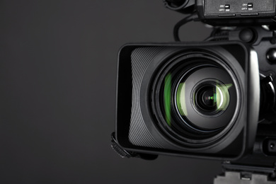 Photo of Modern professional video camera on black background, closeup