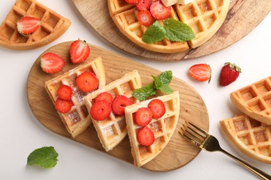 Photo of Tasty Belgian waffles with strawberries, mint and fork on white table, flat lay