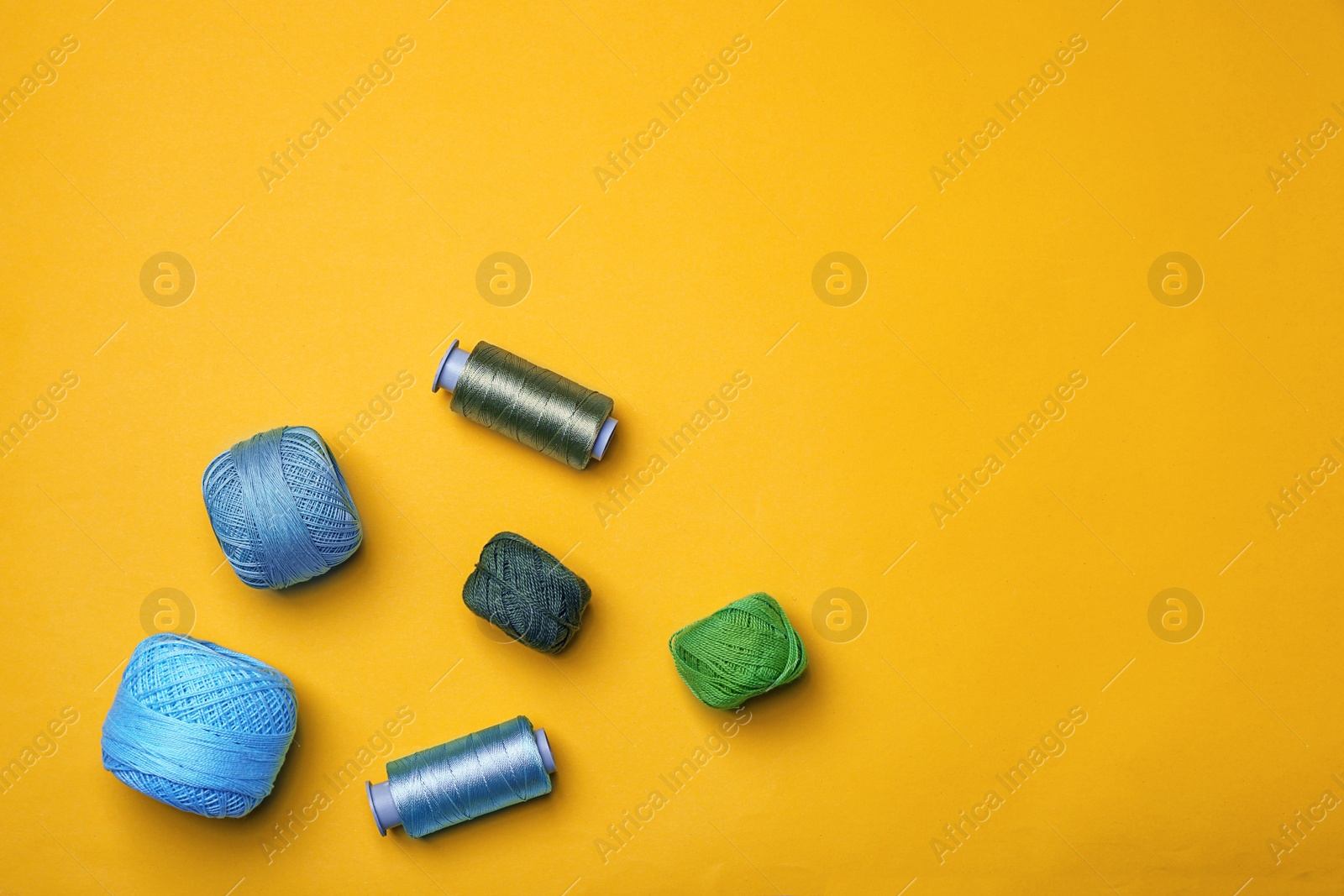 Photo of Flat lay composition with sewing threads on color background